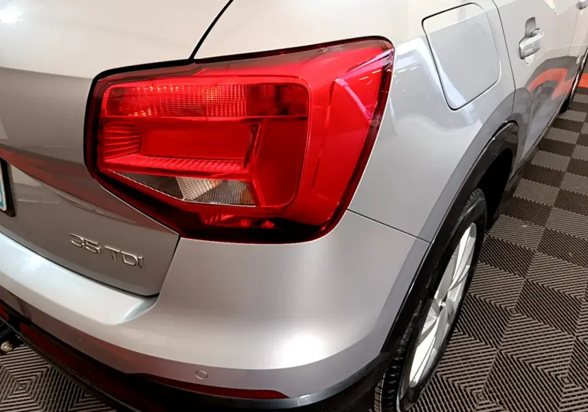 Vue arrière droite d'un Audi Q2 35 TDI gris clair avec feu arrière rouge et logo 35 TDI visible.