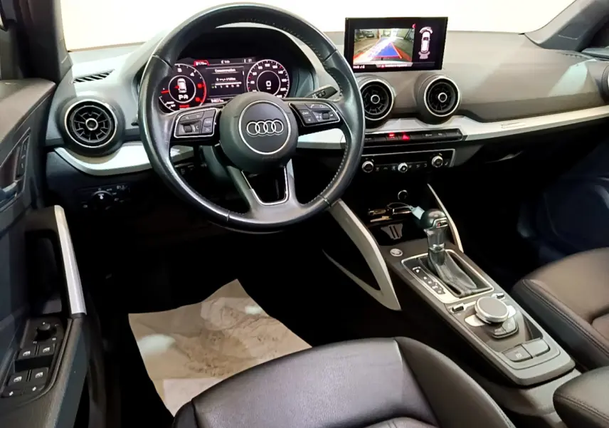 Vue intérieure de l'Audi Q2 35 TDI 150 Design 2020, tableau de bord noir avec écran central et volant cuir multifonctions.