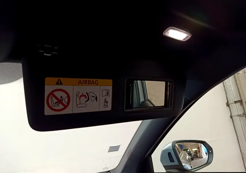 Détail du pare-soleil côté conducteur avec miroir et avertissement airbag, rétroviseur extérieur gris clair d’un Audi Q2 2020.