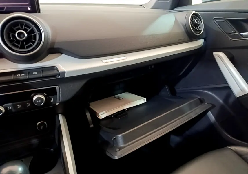 Intérieur de l'Audi Q2 35 TDI 150 Design 2020, vue côté passager sur la boîte à gants ouverte avec manuel Audi.