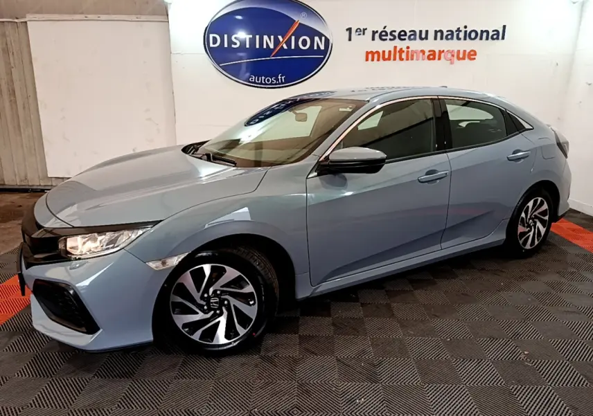 Honda Civic 1.0 i-VTEC Exclusive gris foncé vue 3/4 avant droit dans un showroom avec logo Distinxion.