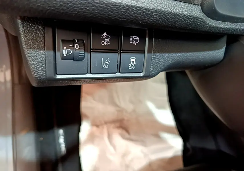 Boutons de réglage des phares et aides à la conduite sous le tableau de bord d'une Honda Civic 1.0 i-VTEC Exclusive gris foncé de 2020.