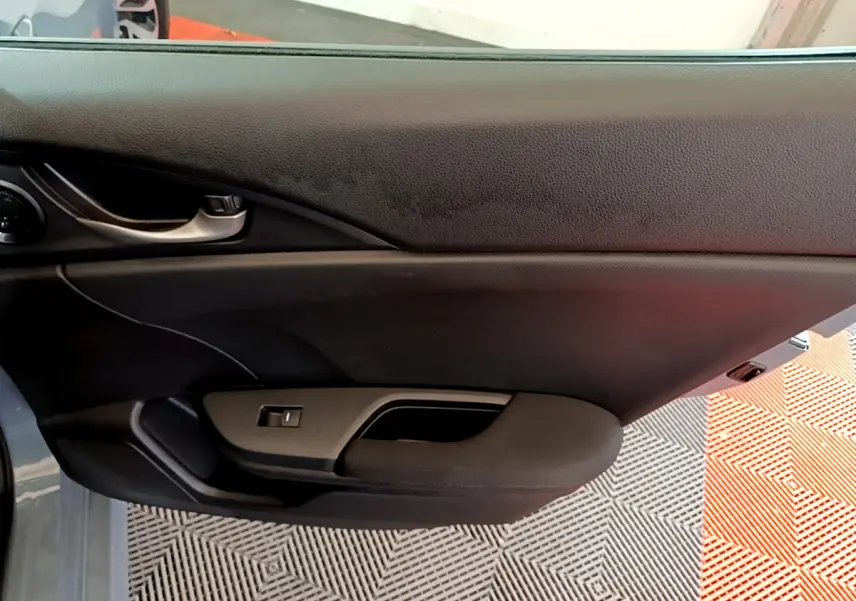 Intérieur montrant la porte côté gauche de la Honda Civic 1.0 i-VTEC Exclusive 2020 en gris foncé, avec poignée et commande vitre.