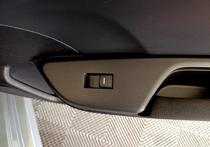 Détail du bouton d'ouverture du toit ouvrant électrique sur la garniture intérieure noire d'une Honda Civic gris foncé.