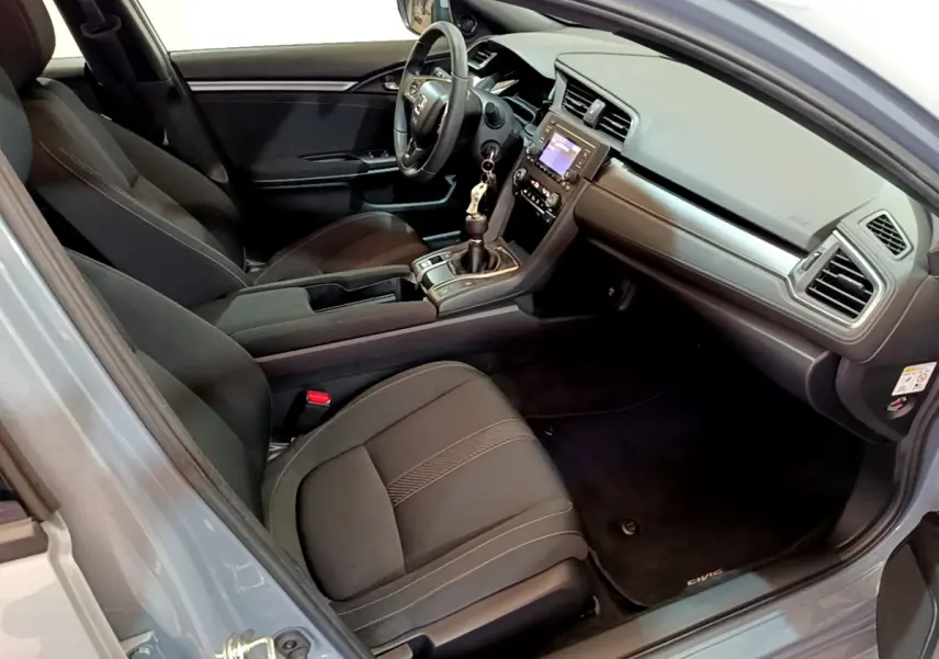 Intérieur avant droit de la Honda Civic 1.0 i-VTEC gris foncé, avec tableau de bord moderne et boîte manuelle.