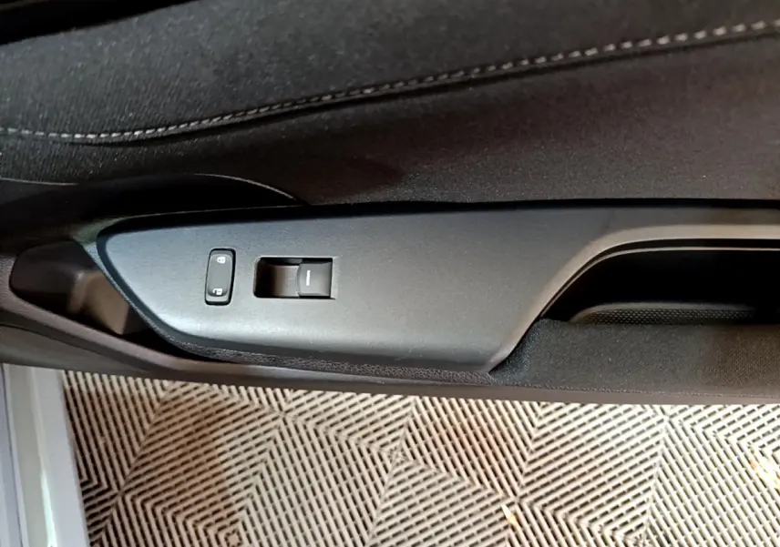 Gros plan sur la commande de verrouillage et lève-vitre côté gauche de la porte intérieure noire d'une Honda Civic gris foncé 2020.