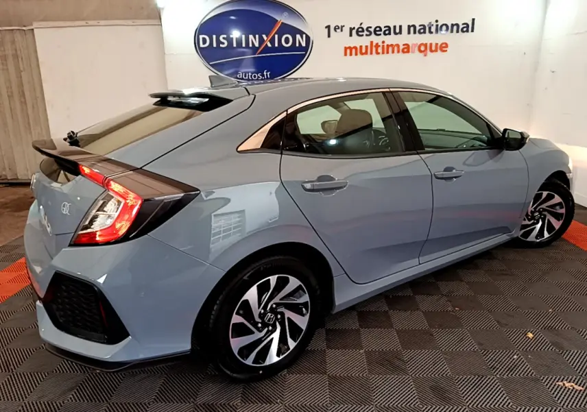 Vue 3/4 arrière droite d'une Honda Civic gris foncé 2020 avec jantes alliage et feux arrière allumés dans un showroom.
