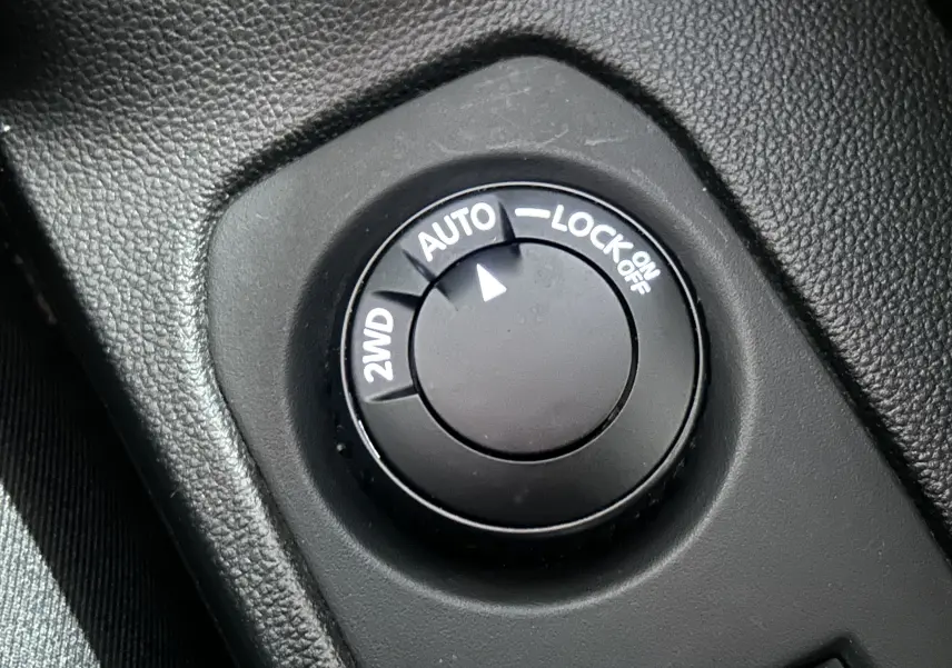 Gros plan sur le sélecteur de mode de traction 2WD, AUTO et LOCK dans l’habitacle noir du Dacia Duster blanc 2024.