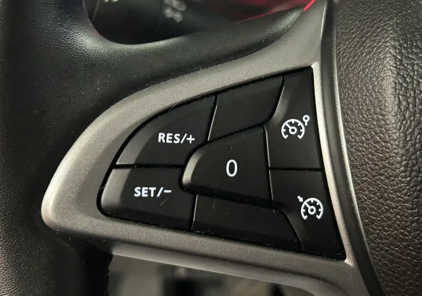 Gros plan sur les commandes de régulateur de vitesse au volant noir du Dacia Duster 2024.