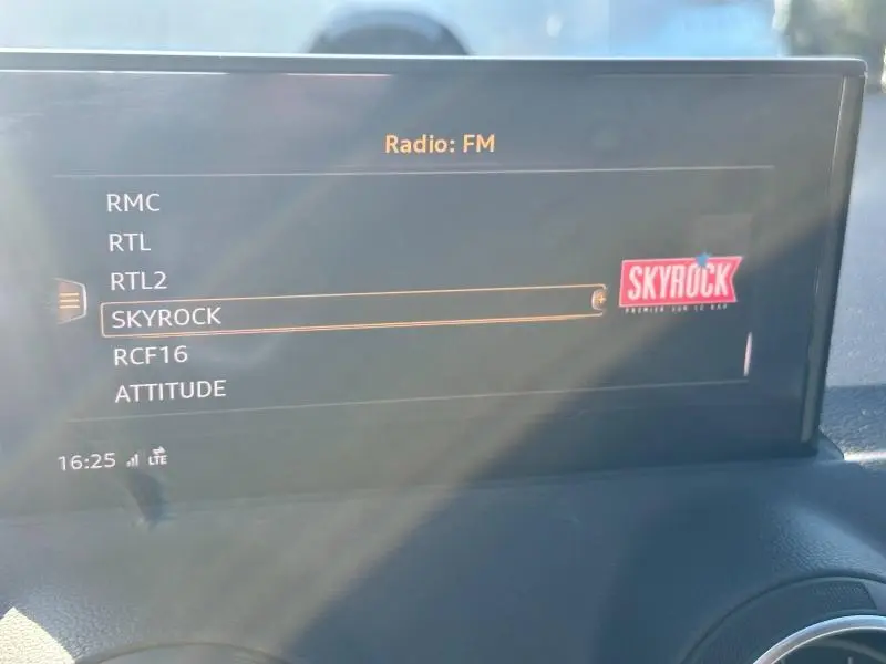 Écran multimédia de l'Audi Q2 blanc 2023 affichant la liste des radios FM, avec Skyrock sélectionné.