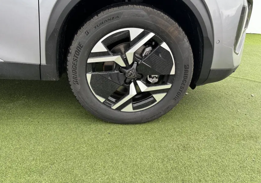 Gros plan sur la roue avant droite du Peugeot 2008 gris Artense avec jante alliage bi-ton noir et argent.