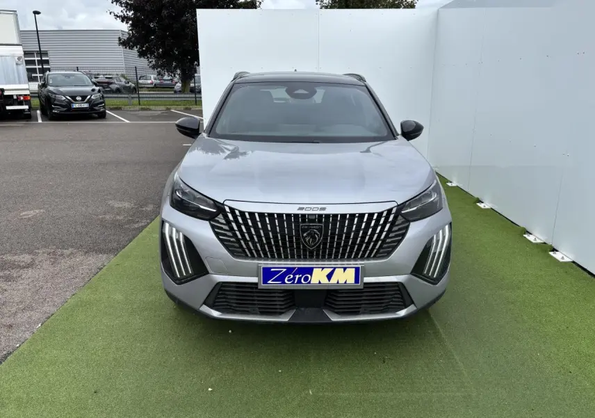 Vue de face du Peugeot 2008 gris Artense avec calandre verticale noire et feux LED 3 griffes allumés.