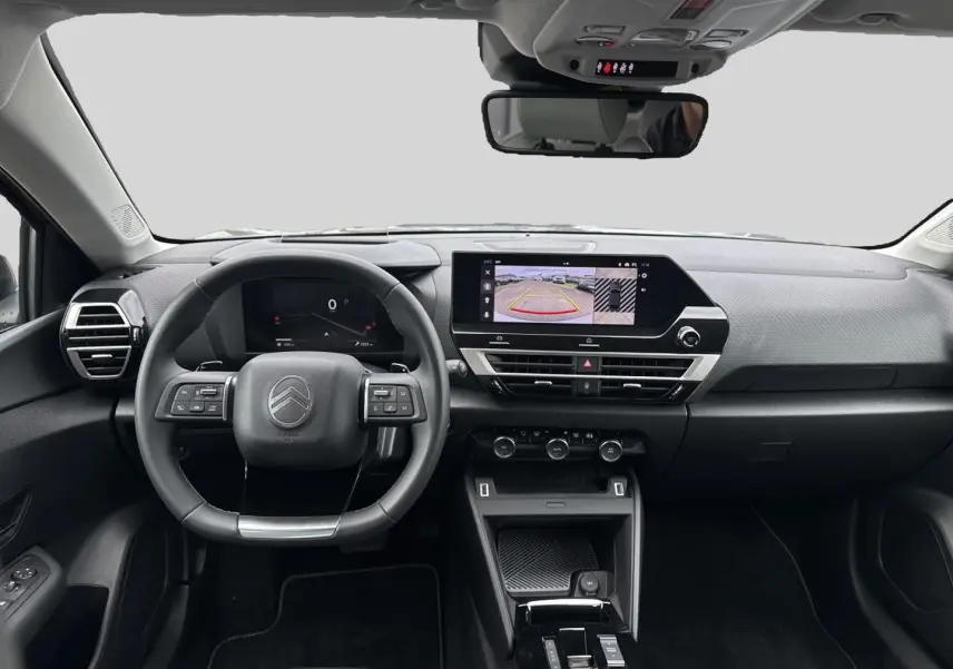 Vue frontale de l'habitacle gris du Citroën C4 X 1.2 hybride 2025, avec écran tactile et volant multifonctions.