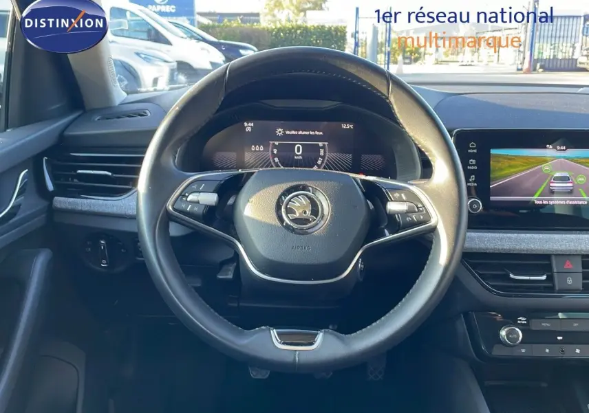 Vue intérieure centrée sur le volant noir du Skoda Kamiq 2024 avec tableau de bord digital et écran tactile.