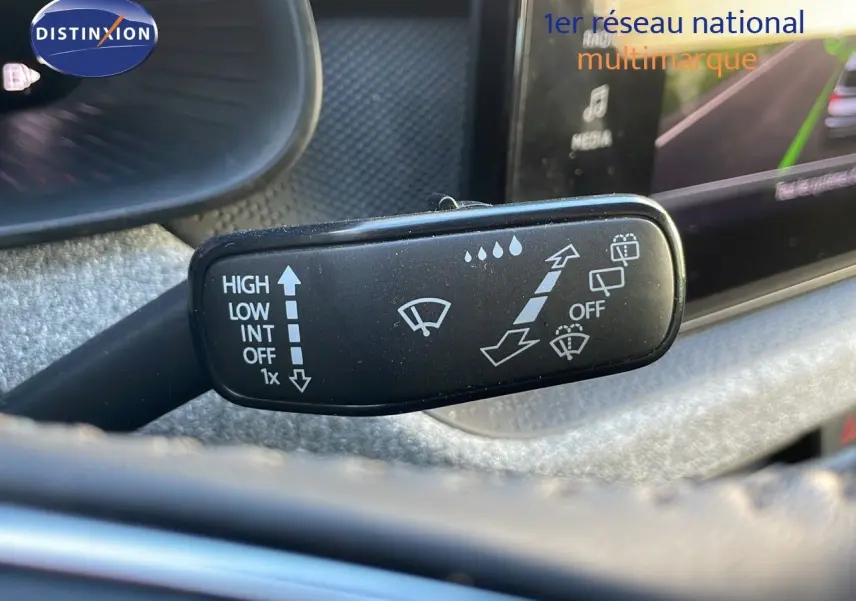 Gros plan sur le commodo d’essuie-glace du Skoda Kamiq noir magique métal 2024, avec commandes visibles et tableau de bord flou.