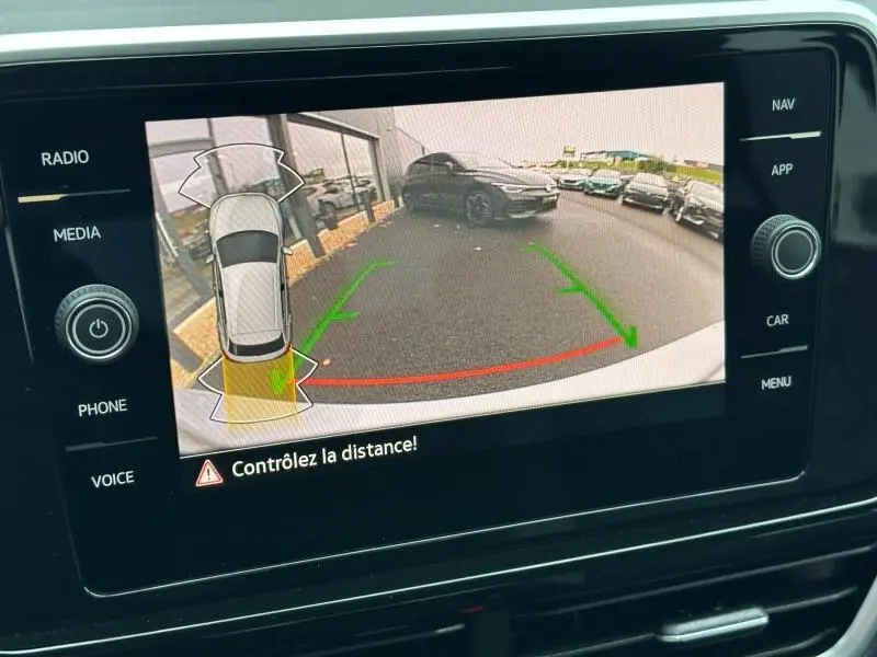 Écran multimédia montrant la caméra de recul du Volkswagen T-Roc gris 2025 avec guidage de trajectoire verte et rouge.