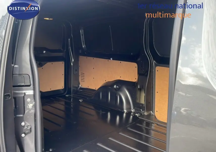 Vue intérieure du coffre arrière ouvert du Citroën Jumpy gris titane, montrant l’espace de chargement vide avec panneaux bois.