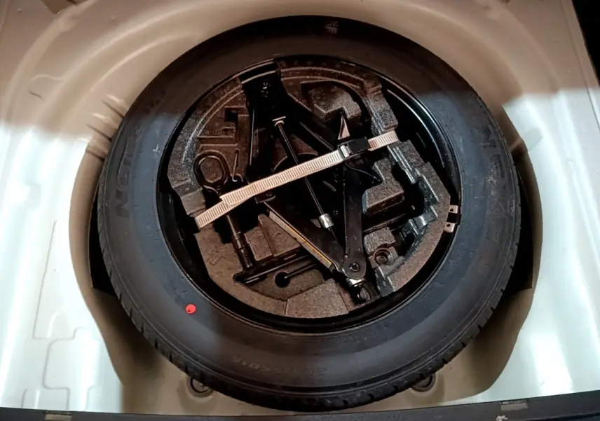 Gros plan sur la roue de secours en jante acier noire dans le coffre blanc d'une Skoda Superb 2021.