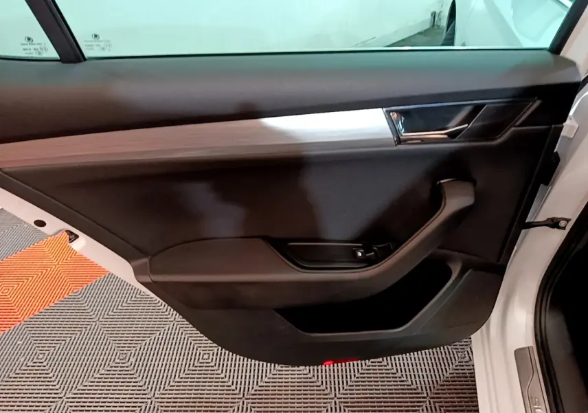 Vue rapprochée de la porte avant gauche noire avec insert décoratif bois sur une Skoda Superb blanche 2021.