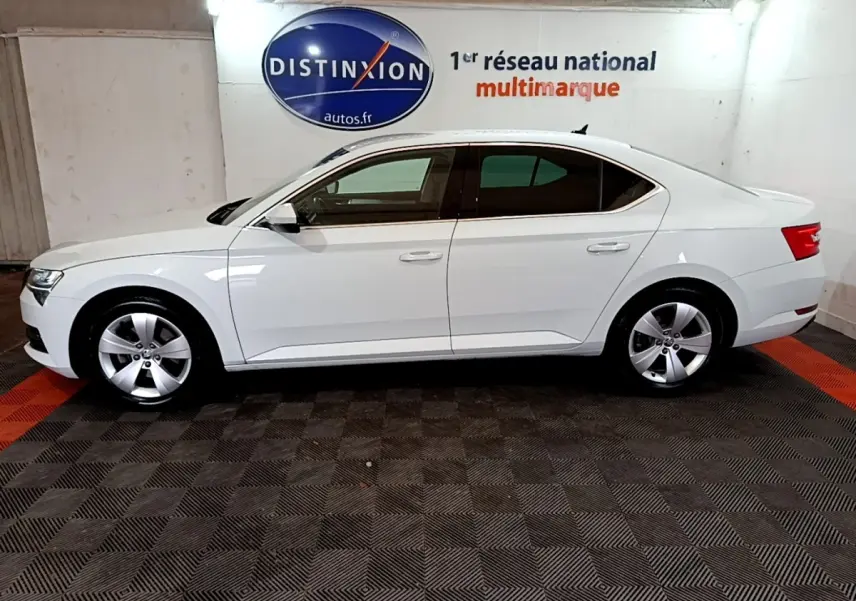 Vue de profil côté gauche d'une Skoda Superb blanche de 2021, berline élégante avec jantes alliage et vitres teintées.