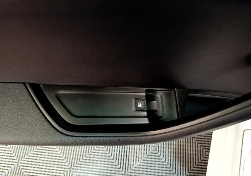 Détail de la poignée intérieure de porte côté conducteur d’une Skoda Superb blanche, bouton de verrouillage visible.