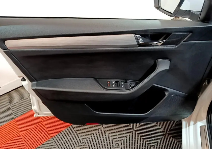 Vue intérieure côté gauche de la porte avant blanche d'une Skoda Superb 2021, avec garniture noire et insert bois.