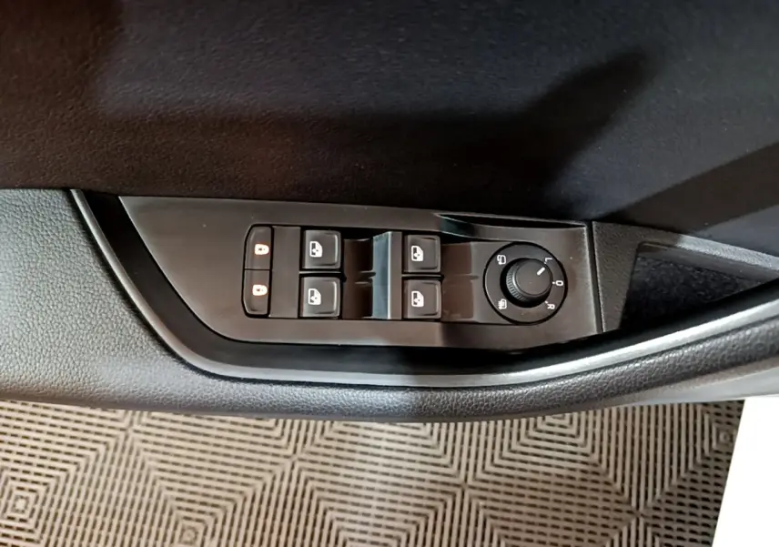 Vue rapprochée des commandes de lève-vitres et réglage des rétroviseurs côté conducteur d'une Skoda Superb blanche.