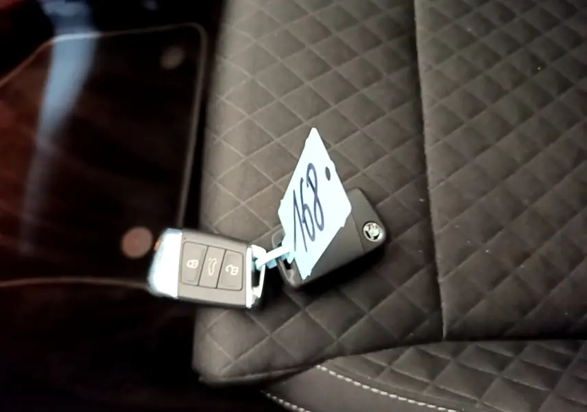 Gros plan sur la clé de voiture SKODA posée sur un siège intérieur noir matelassé avec étiquette numérotée.