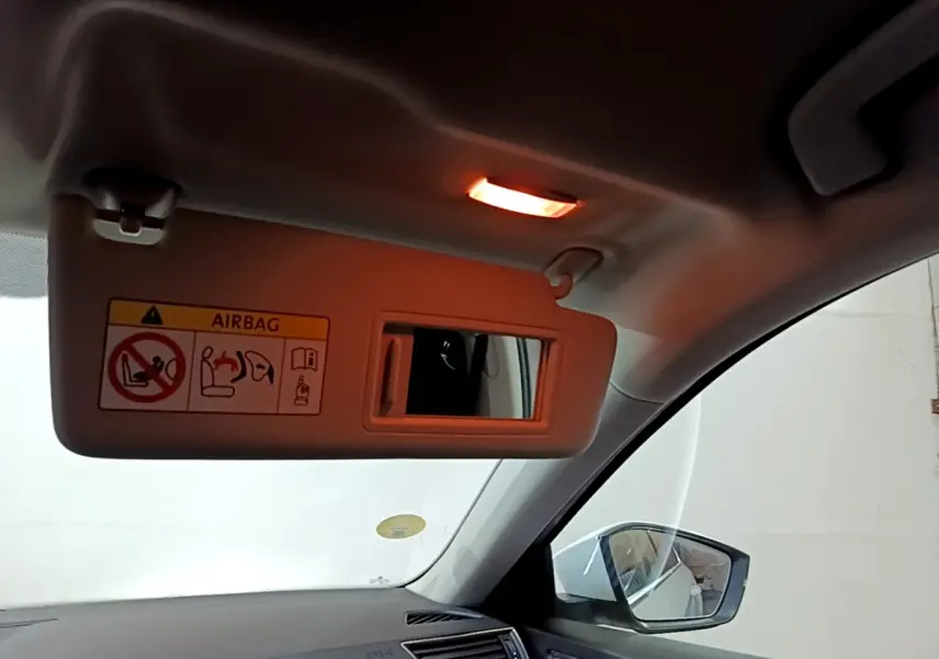 Détail intérieur du pare-soleil côté conducteur avec miroir et lumière allumée dans une Skoda Superb blanche.