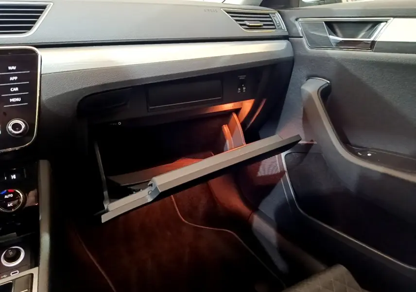 Intérieur de la Skoda Superb 2021, vue côté passager sur la boîte à gants ouverte avec éclairage intérieur orange.