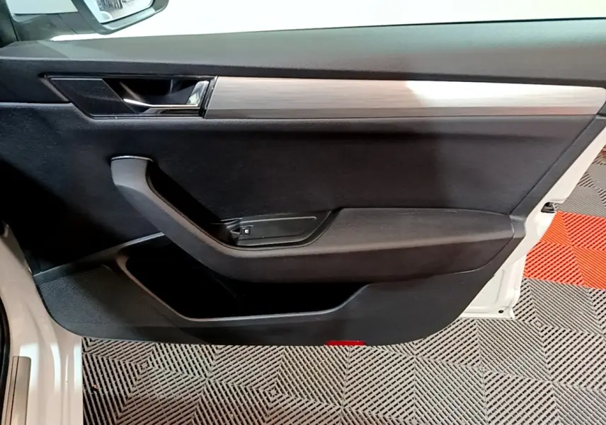 Vue intérieure de la porte avant gauche noire avec insert décoratif bois clair de la Skoda Superb blanche 2021.