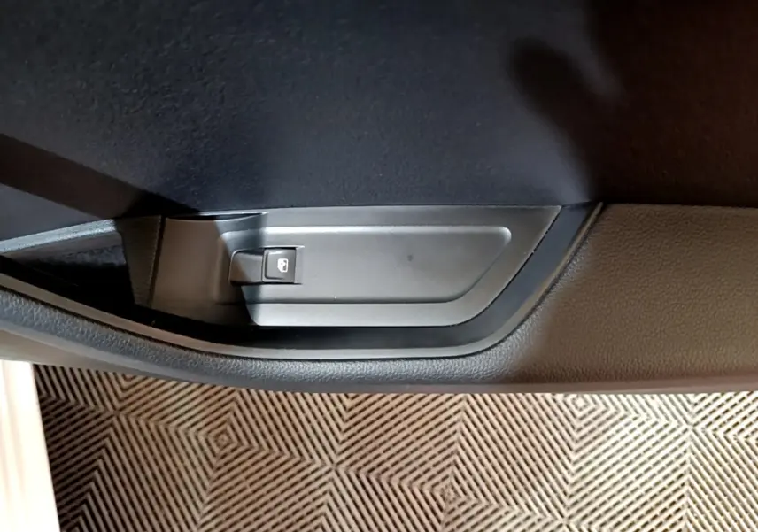 Gros plan sur le bouton de verrouillage de porte noir dans l'habitacle d'une Skoda Superb blanche, côté intérieur.