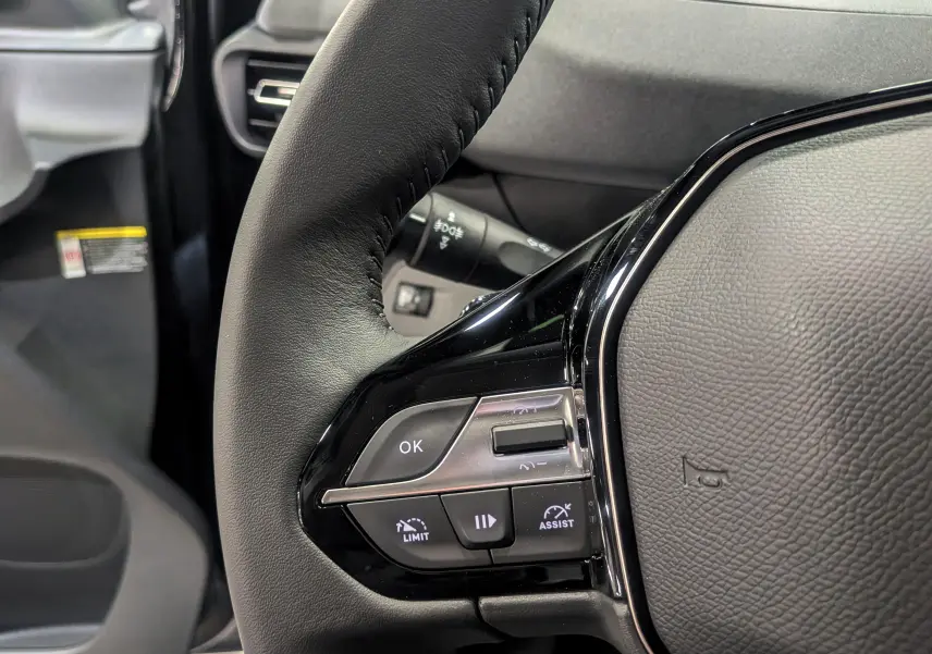 Gros plan sur le volant cuir noir du Peugeot Rifter 2025, mettant en valeur les commandes intégrées côté gauche.