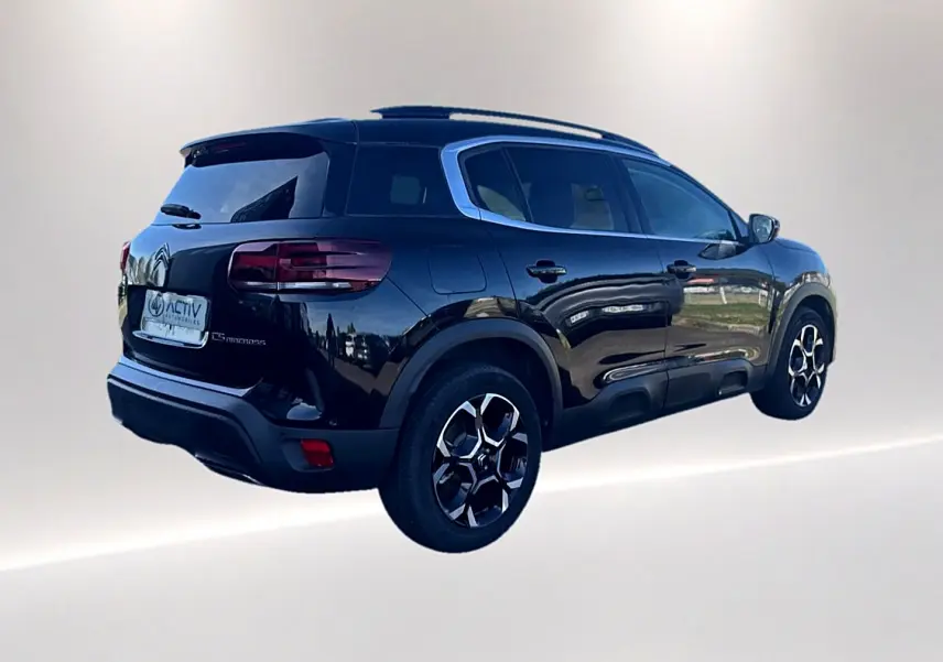 Citroën C5 Aircross noir vue 3/4 arrière droit avec barres de toit et jantes alu distinctives.