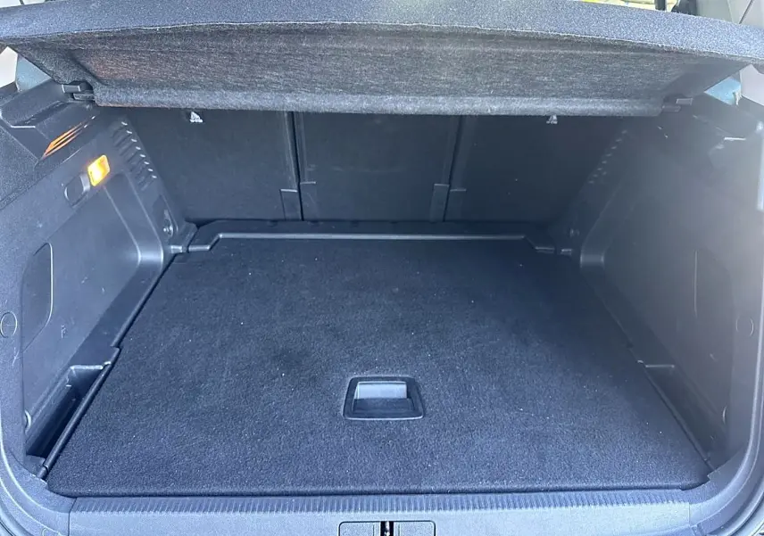 Coffre ouvert noir du Citroën C5 Aircross 1.2 hybride 145, vue arrière montrant le plancher plat et l'éclairage intérieur.