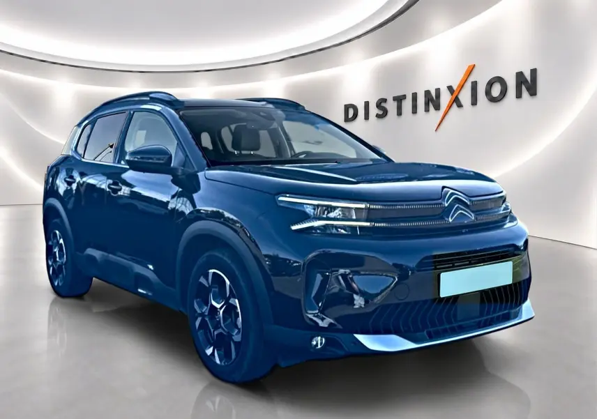 Citroën C5 Aircross noir en 3/4 avant droit dans un showroom avec jantes alu et barres de toit visibles.