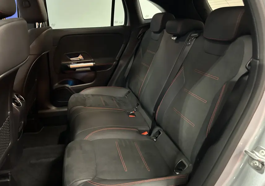 Vue intérieure arrière droite des sièges noirs avec surpiqûres rouges du Mercedes GLA 200 D AMG Line 2024 argent High-tech.