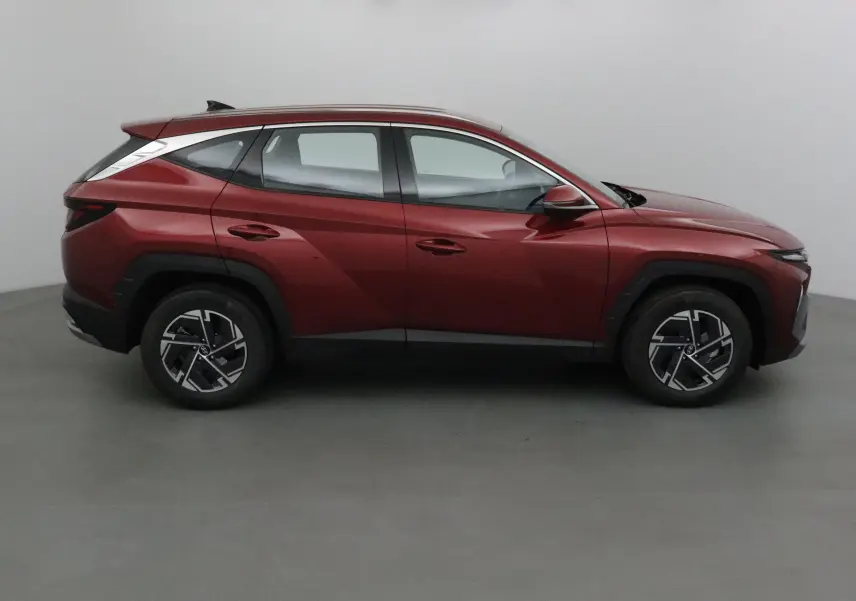 Vue latérale droite du Hyundai Tucson 2025 rouge Ultimate avec jantes alliage et lignes anguleuses marquées.
