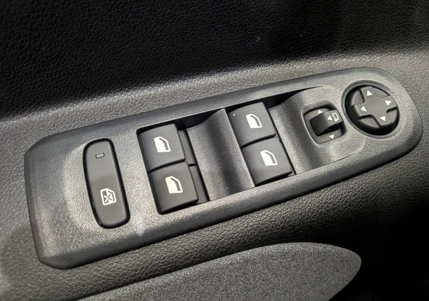 Gros plan sur les commandes de lève-vitres et réglage des rétroviseurs côté conducteur du Peugeot Rifter noir 2025.