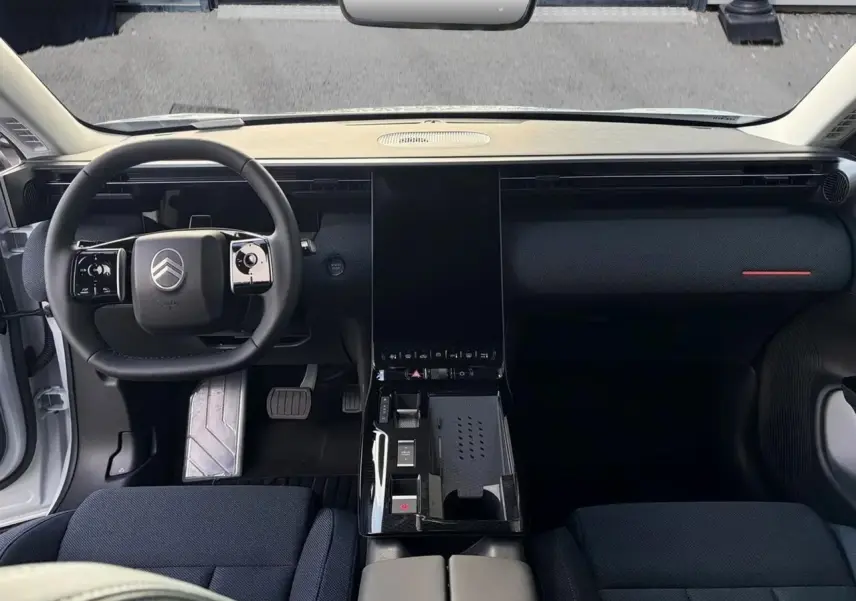 Vue intérieure frontale du tableau de bord noir et volant Citroën du C5 Aircross hybride 2026, sièges tissu bleu.