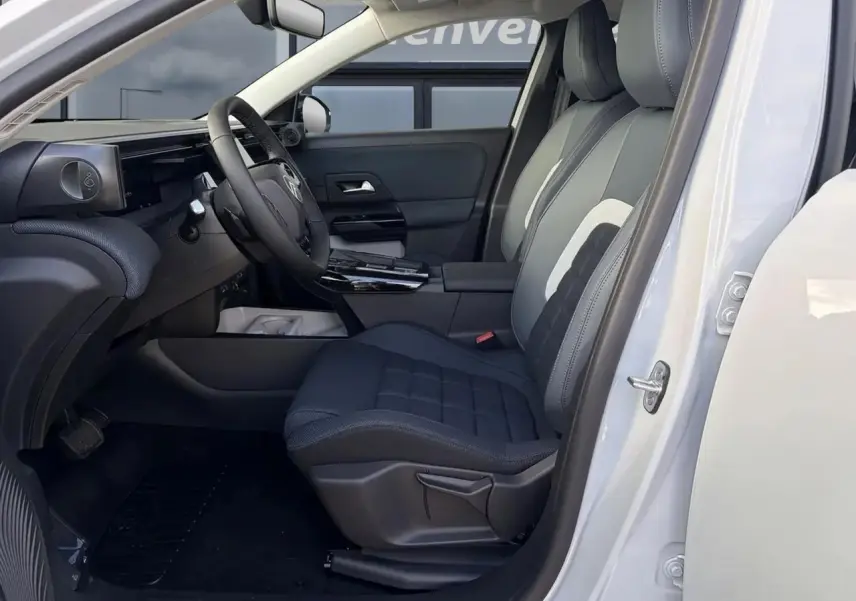 Vue intérieure côté conducteur du Citroën C5 Aircross blanc, mettant en valeur les sièges tissu bleu et le volant multifonction.