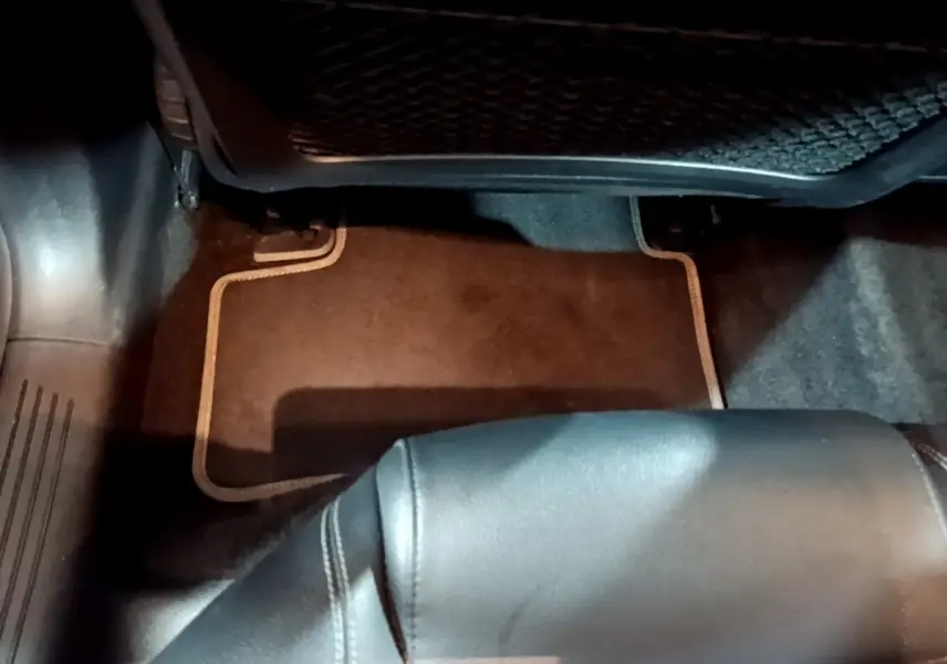 Vue intérieure du plancher côté passager arrière d'une Mercedes CLA 180 d Business Line gris clair avec tapis de sol noir.