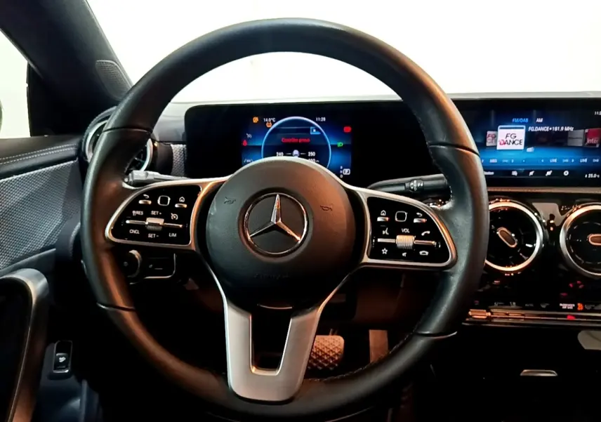 Vue rapprochée du volant cuir noir de la Mercedes CLA 180 d 2021 avec tableau de bord numérique et commandes intégrées.