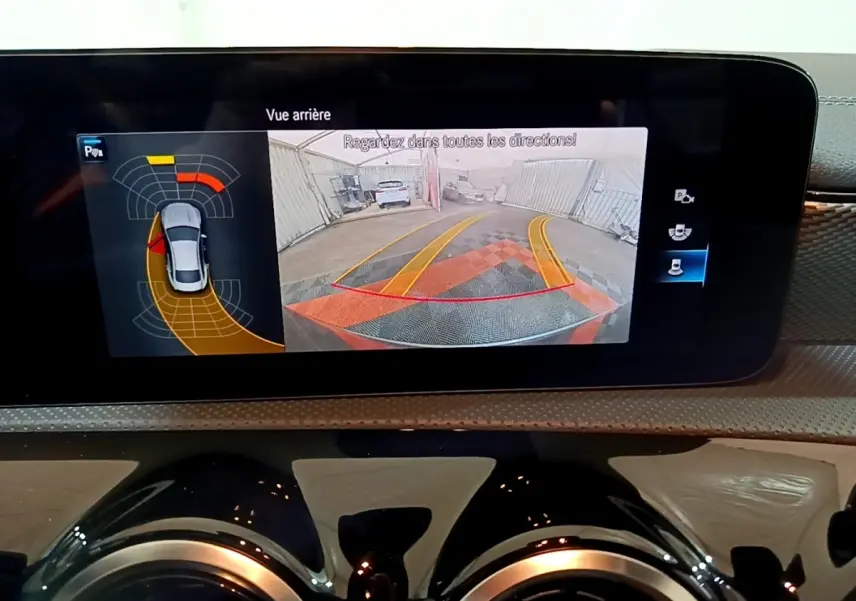 Affichage de la caméra de recul et des capteurs de stationnement sur l'écran tactile du tableau de bord d'une Mercedes CLA 180 d gris clair.