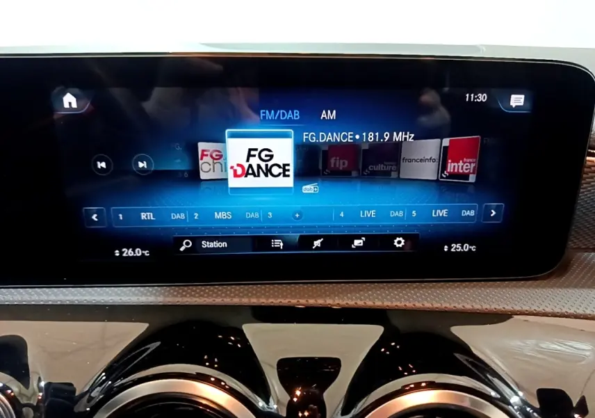 Écran tactile central affichant la radio FM/DAB dans l’habitacle d’une Mercedes CLA 180 d gris clair.