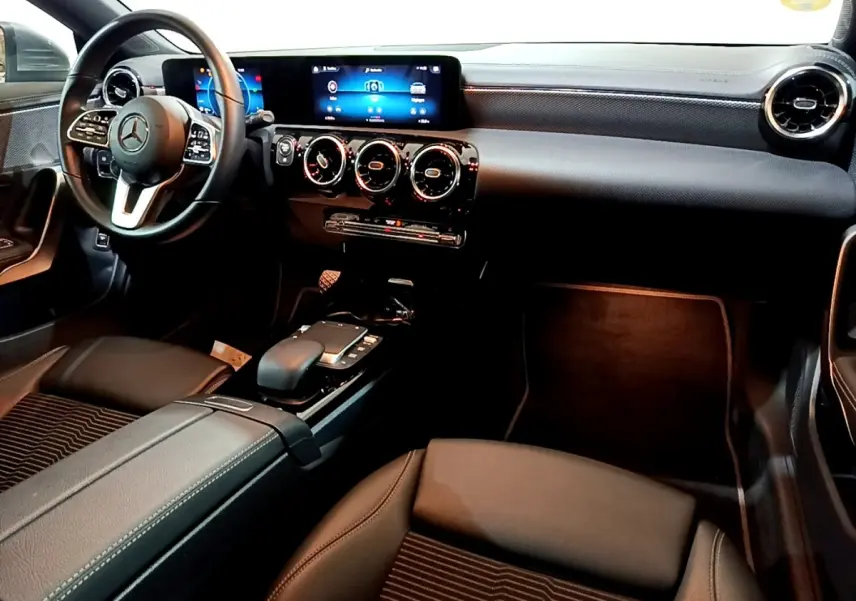 Vue intérieure avant droite de la Mercedes CLA 180 d Business Line 2021, tableau de bord noir avec écran tactile et volant cuir.
