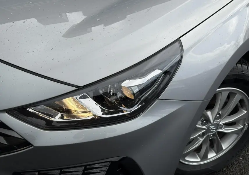 Gros plan sur le phare avant droit et la jante alliage gris argent d'une Hyundai i30 SW T-GDI 120 Modern 2025.