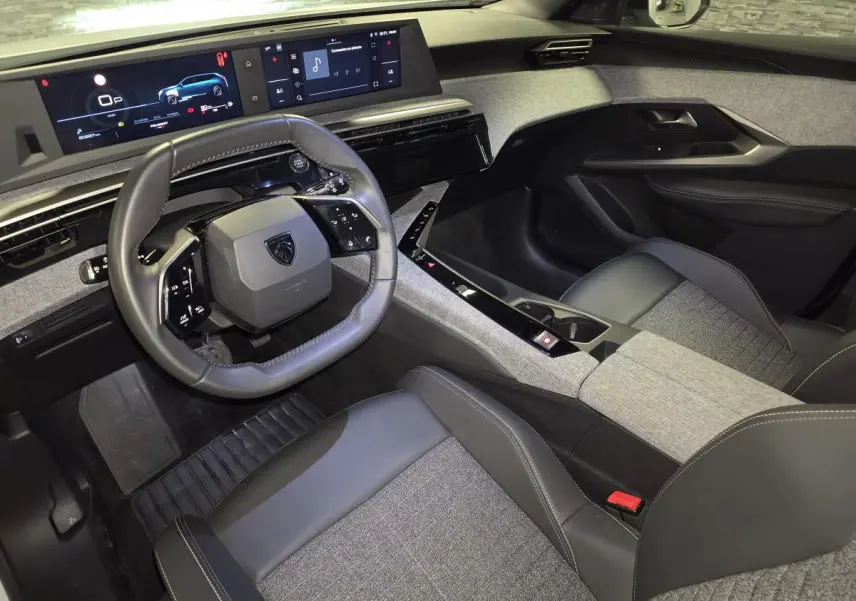 Vue intérieure côté conducteur du Peugeot 5008 2025, volant compact cuir noir et tableau de bord avec double écran HD.
