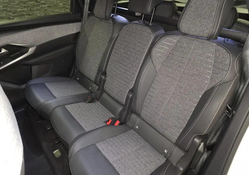 Vue intérieure sur la banquette arrière tissu gris et cuir noir du Peugeot 5008 blanc 2025, avec ceintures et appuie-têtes.