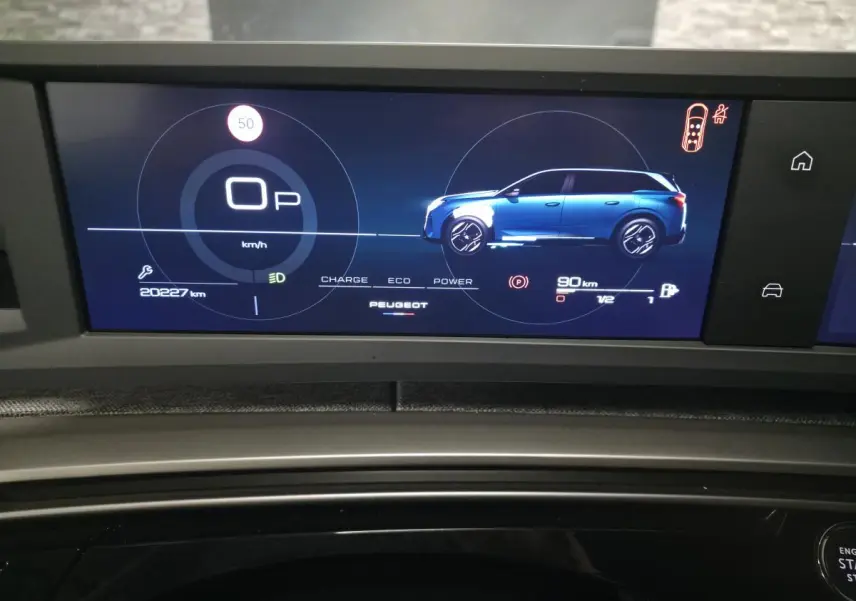 Affichage numérique du tableau de bord du Peugeot 5008 blanc, montrant la vitesse et la silhouette latérale du véhicule.